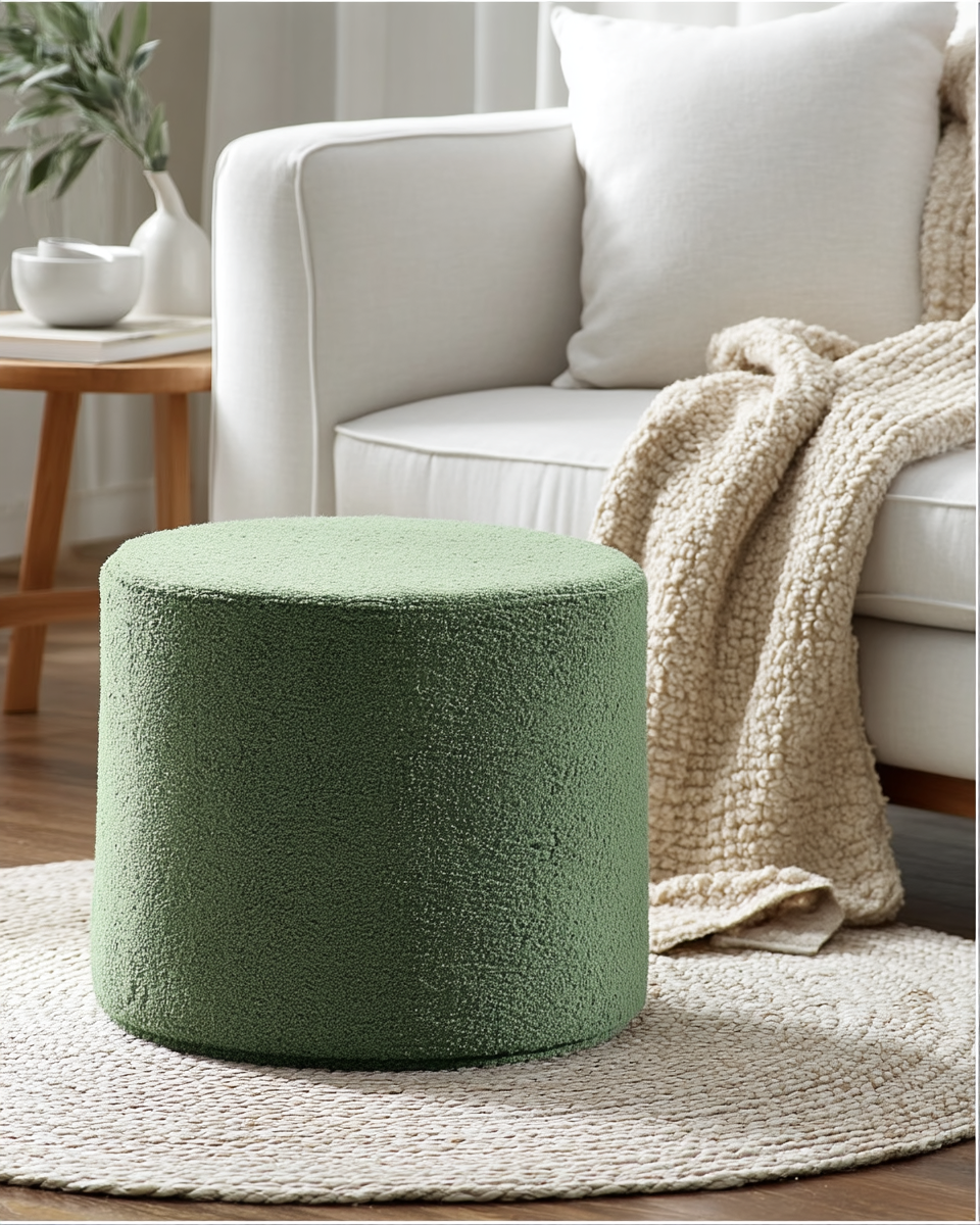 Round sage green bouclé pouf ottoman on a cream rug in front of a white sofa